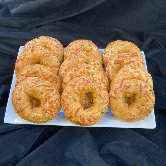 A tray of jalapeno pepper jack bagels on a white plate against a dark background.