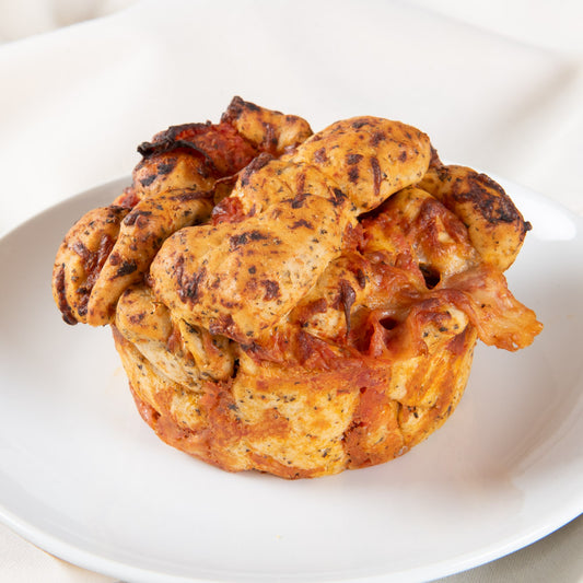 A mini pepperoni pizza focaccia showing its pull-apart layers with tomato sauce and melted cheese, served on a white plate.