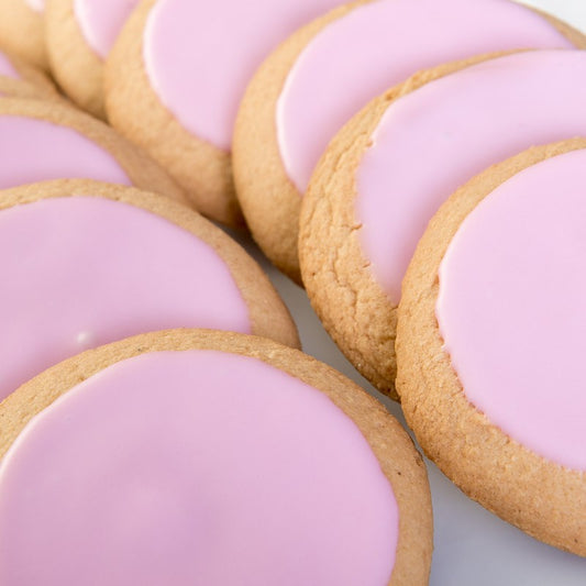 A close up of sugar cookies, topped with smooth pink icing.
