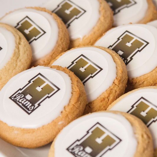 Round frosted sugar cookies topped with a white fondant disc printed with a gold and black Rams logo.