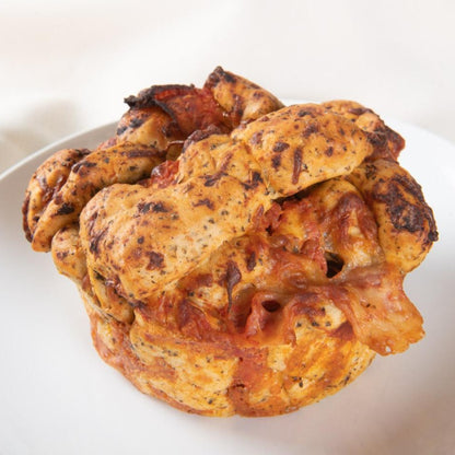 A mini pepperoni pizza focaccia with a golden herb-seasoned crust, melted cheese, and tomato sauce, served on a white plate.