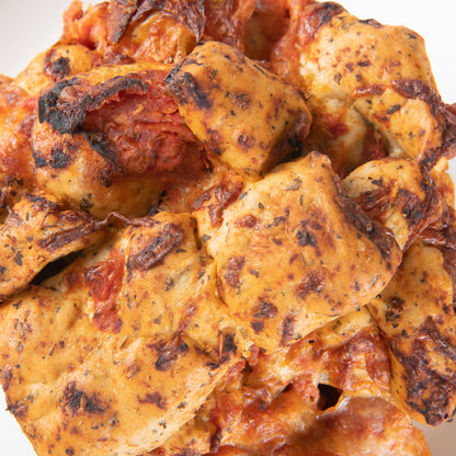 A close-up view of a mini pepperoni pizza focaccia showing its pull-apart layers with tomato sauce and melted cheese.