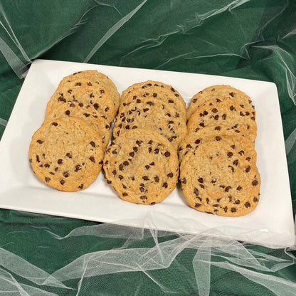 A tray of vegan chocolate chip cookies on a white plate against a green background.
