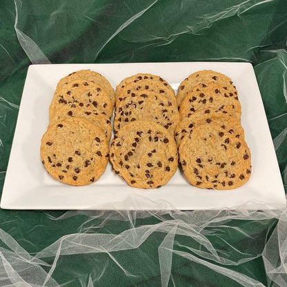 A vegan chocolate chip cookies on a white plate against a green background.